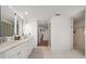 A bright bathroom featuring a long marble vanity, dual sinks, tile floor, and decorative glass block accent at 213 Harrison Ave, Belleair Beach, FL 33786