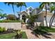 Charming two-story home with a brick walkway, lush greenery, and coastal charm at 213 Harrison Ave, Belleair Beach, FL 33786