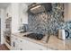 Close-up of kitchen with stainless appliances, granite countertops, and mosaic tile backsplash at 213 Harrison Ave, Belleair Beach, FL 33786