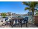 Cozy waterfront outdoor dining area with seating for six, surrounded by lush landscaping and serene water views at 213 Harrison Ave, Belleair Beach, FL 33786