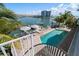 Aerial view of a waterfront home with a pool, hot tub, private dock, boat lift, and outdoor lounge area at 213 Harrison Ave, Belleair Beach, FL 33786