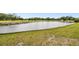 Picturesque community pond surrounded by lush green grass and rock retaining wall at 2614 Cove Cay Dr # 207, Clearwater, FL 33760