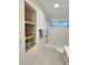 Bright white bathroom with built in decorative shelves, tub, shower and window at 2869 Thistle N Ct, Palm Harbor, FL 34684