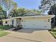 Inviting home exterior featuring a two-car garage, manicured lawn, and lush landscaping at 2869 Thistle N Ct, Palm Harbor, FL 34684