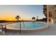 A stunning pool at sunset with lounge chairs, palm trees, and an ocean view at 500 N Osceola Ave # 808, Clearwater, FL 33755