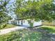 Attractive home featuring a covered porch, manicured landscaping, a mature shade tree, and a paved driveway at 5290 101St Ave, Pinellas Park, FL 33782