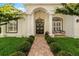Elegant front entrance with a brick walkway, manicured landscaping, and a classic white facade with arched doorway and pillars at 5605 Glencrest Blvd, Tampa, FL 33625