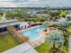 Aerial view of a community pool with orange umbrellas, lounge chairs and mature palm trees at 6326 Waves End Pl, Apollo Beach, FL 33572