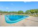 Community pool surrounded by lounge chairs, mature trees, and a fenced-in tennis court at 6920 Lafayette N # 6920, Pinellas Park, FL 33781