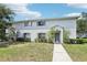 Exterior view of a light grey townhome with a well-kept lawn and sidewalk leading to the entrance at 7303 E Bank Dr, Tampa, FL 33617