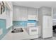 Bright kitchen features stainless steel sink, blue tiled backsplash, and white appliances at 8031 7Th N St, St Petersburg, FL 33702
