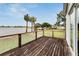 Spacious wooden deck with glass railing overlooking a lake and lush backyard with boats docked nearby at 828 Bayshore Dr, Tarpon Springs, FL 34689