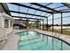 Inviting screened-in pool with clear water, surrounded by a spacious patio and lush landscaping with lake view at 828 Bayshore Dr, Tarpon Springs, FL 34689