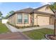 Well-kept house featuring a tan exterior, two-car garage, and manicured lawn, plus attractive landscaping at 8975 Southern Charm Cir, Brooksville, FL 34613