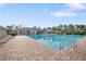 A large pool with lounge chairs, palm trees, and a clubhouse in the background at 8975 Southern Charm Cir, Brooksville, FL 34613