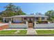 Charming home featuring a white fence, pergola entrance, well-maintained landscaping, and a convenient carport at 101 Pampas Ave, Tarpon Springs, FL 34689