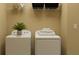 Cozy laundry room with white washer and dryer, shelving, and a plant for a touch of greenery at 11547 E 71St Ter, Palmetto, FL 34221