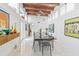 Bright dining room featuring wood beam ceiling, marble floors, modern art and a stainless steel dining table with seating at 1175 Jackson Rd, Clearwater, FL 33755