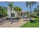 Charming two-story home boasts lush landscaping, a red tile roof, and a brick paved driveway at 1175 Jackson Rd, Clearwater, FL 33755