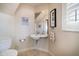Well-lit bathroom with a pedestal sink, toilet, framed artwork, and natural light from window at 118 94Th Ave, Treasure Island, FL 33706