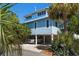 Charming stilt home with beachy blue siding, lush landscaping, and convenient covered parking at 118 94Th Ave, Treasure Island, FL 33706