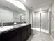 Bathroom featuring double vanity with granite countertop and walk-in shower with glass door at 11823 Dumaine Valley Rd, Riverview, FL 33579