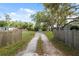 Gravel driveway leads up to a metal carport, and a fenced yard on a sunny day at 12430 Oconee Blvd, New Port Richey, FL 34654