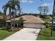 Inviting single-story home with a tile roof, three-car garage, manicured lawn, and tropical landscaping at 1311 Fallsmeade Ct, Oldsmar, FL 34677