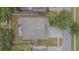 This aerial view shows a home with a gravel patio, green lawn, mature trees, and a paved driveway and street at 1418 Rushgrove Cir, Dover, FL 33527