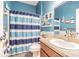 Nautical-themed bathroom with blue walls, striped shower curtain, and granite countertop vanity at 1418 Rushgrove Cir, Dover, FL 33527