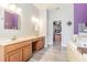Bathroom with double sinks, wood-look flooring, walk-in closet, and soaking tub at 1418 Rushgrove Cir, Dover, FL 33527