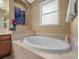 Close up shot of a luxurious tub with a neutral tile surround, steps, and accent art at 15254 Bellamy Rd, Tampa, FL 33625