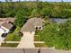 Expansive aerial view of a beige house featuring a three-car garage surrounded by mature trees at 15254 Bellamy Rd, Tampa, FL 33625