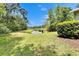 This backyard features a beautiful lawn, a pond, and mature trees at 15825 Fishhawk View Dr, Lithia, FL 33547