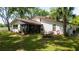 Beautiful backyard featuring a screened porch, outdoor dining set, lush lawn, and mature trees at 1691 Ridge Top Dr, Tarpon Springs, FL 34688
