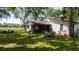 Picturesque backyard featuring a screened porch, outdoor dining set, mature trees, and lush green lawn at 1691 Ridge Top Dr, Tarpon Springs, FL 34688