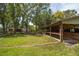 A barn with open stalls overlooks a large, lush lawn leading to a quaint house in the background at 1691 Ridge Top Dr, Tarpon Springs, FL 34688