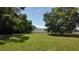 Spacious grassy area with mature trees and a large outbuilding, perfect for rural living and hobbies at 1691 Ridge Top Dr, Tarpon Springs, FL 34688