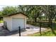 A detached one-car garage features a concrete driveway and beautiful, mature trees in a fenced yard at 1691 Ridge Top Dr, Tarpon Springs, FL 34688