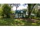 View of an outdoor shed with a green roof and wooden plank door amid the backyard's grassy lawn at 1691 Ridge Top Dr, Tarpon Springs, FL 34688