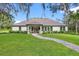 Expansive backyard featuring lush lawn, a covered patio, and a charming brick pathway at 17320 Nokota Ave, Hudson, FL 34667