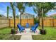 Cozy backyard patio features Adirondack chairs around a concrete pad, wooden fence, and string lights at 2215 Thrace St, Tampa, FL 33605