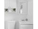 Well-lit bathroom with a white sink, toilet, vanity mirror, and a small plant shelf at 2215 Thrace St, Tampa, FL 33605