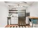 Compact kitchenette with stainless steel refrigerator, white cabinetry, open shelving, and a charming blue microwave at 2215 Thrace St, Tampa, FL 33605