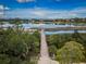 Aerial view of wooden fishing pier stretching out over lake surrounded by lush foliage, and homes in the distance at 2392 Hillcreek E Cir, Clearwater, FL 33759