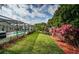 Lush backyard with well-manicured landscaping, complemented by a screened-in pool area at 2392 Hillcreek E Cir, Clearwater, FL 33759