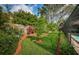 Green backyard with small fruit trees, mulch, bordered by garden beds and a screened-in pool at 2392 Hillcreek E Cir, Clearwater, FL 33759