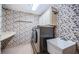 Compact laundry room featuring washer, dryer, storage cabinets, utility sink, and patterned wallpaper at 2392 Hillcreek E Cir, Clearwater, FL 33759
