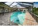 Exterior view of a screened-in pool, brick paver surround, and hot tub with lush landscaping at 2392 Hillcreek E Cir, Clearwater, FL 33759