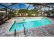 Beautiful screened-in pool with brick paver surround and separate hot tub surrounded by lush landscaping at 2392 Hillcreek E Cir, Clearwater, FL 33759